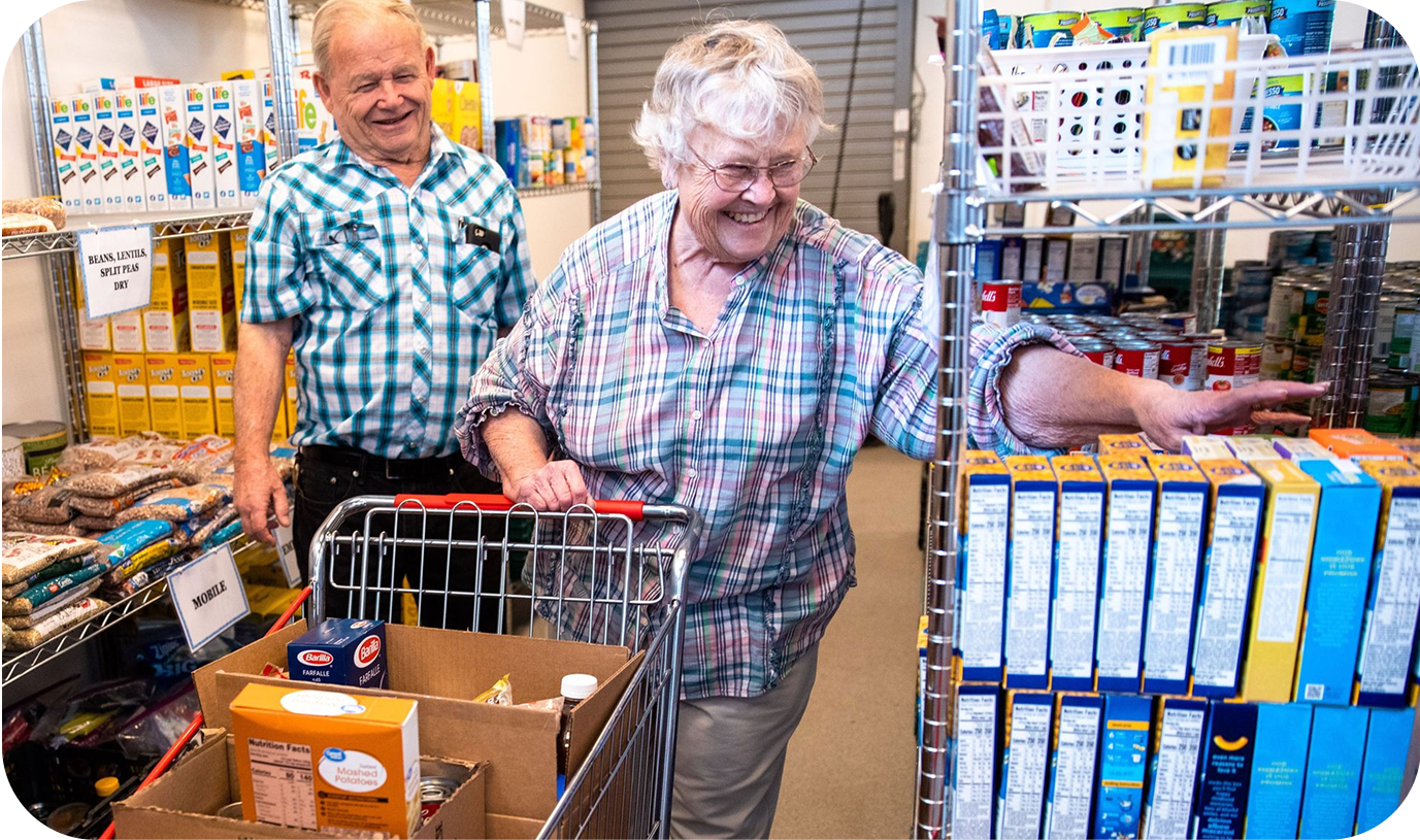 A woman with a shopping cart in a community food pantry gathering groceries