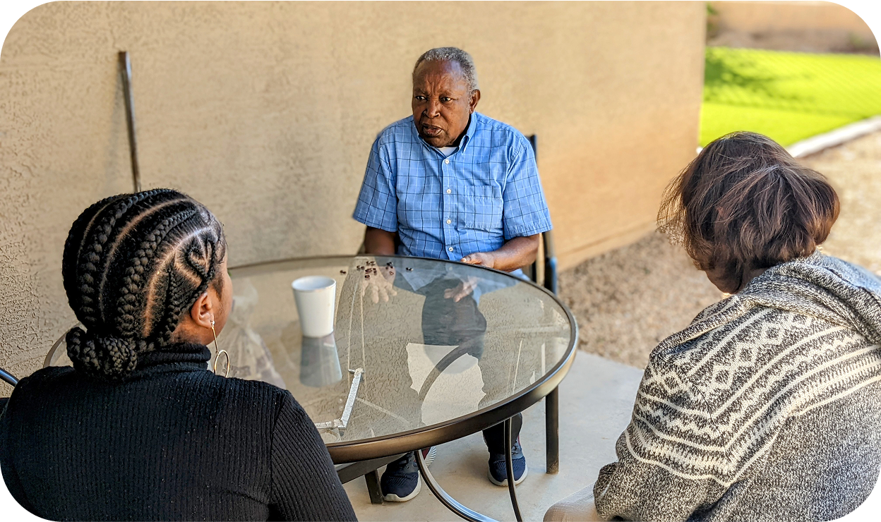 A family of 3 hanging around a table outdoors